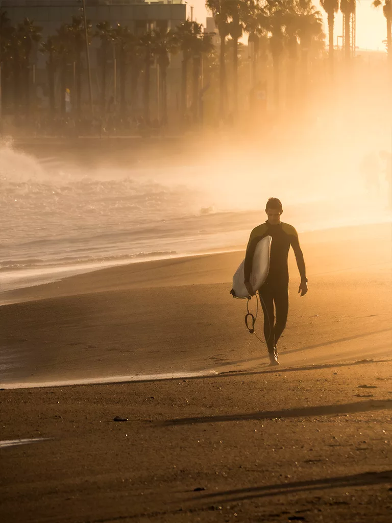 Un surfeur profite du coucher de soleil et de la magnifique lumière sur le plage de la barceloneta.